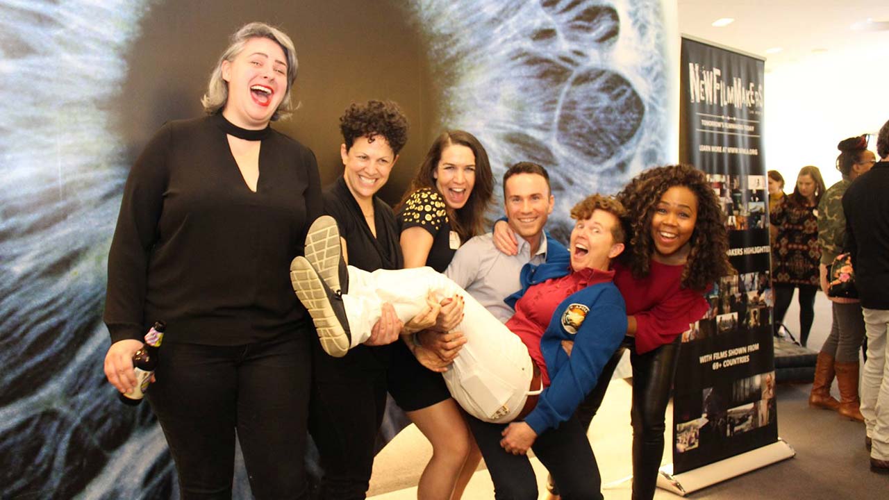 A group of five laughing people pick up their friend.